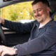 Man sat in the front seat using car interface.